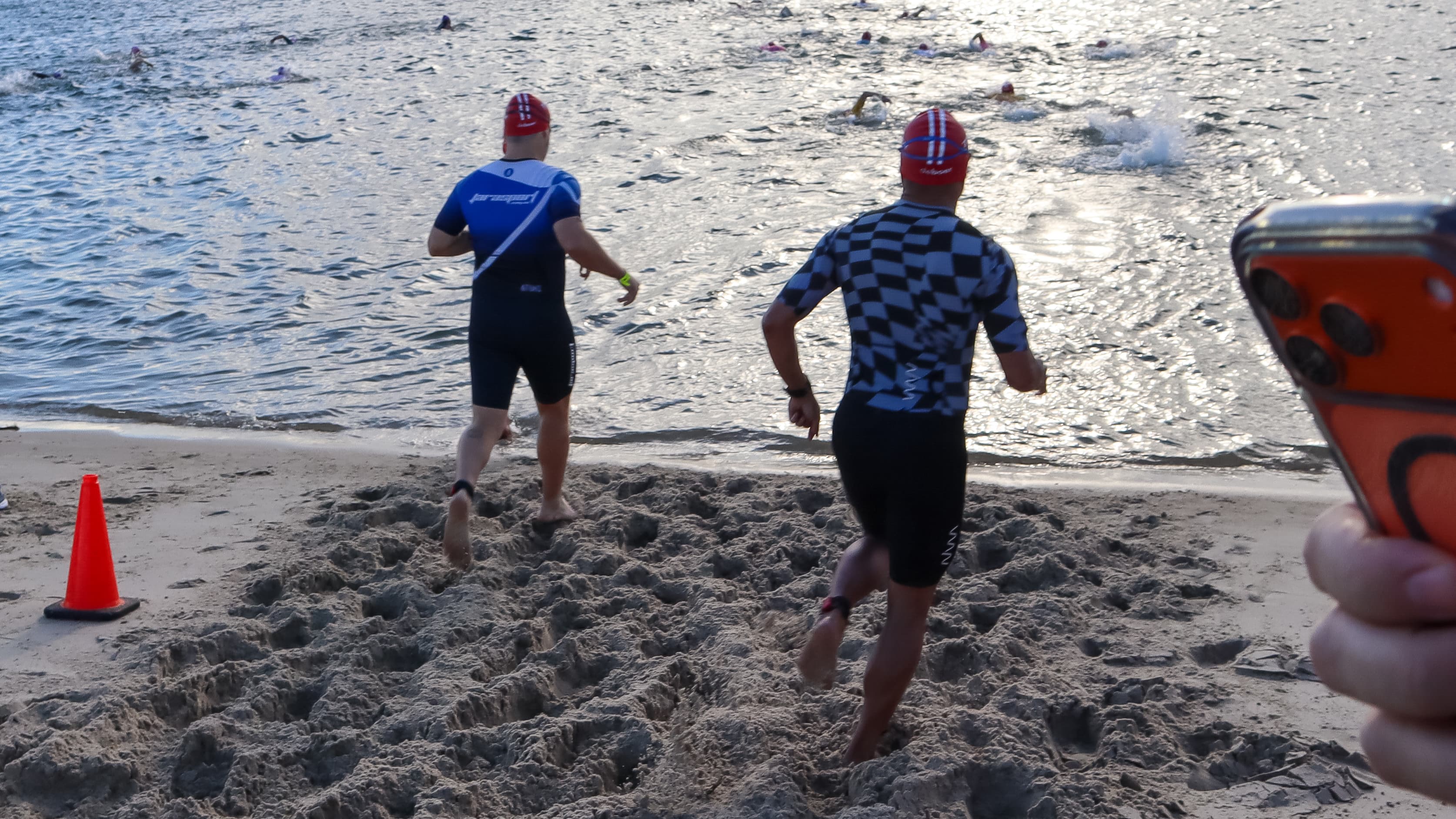 Two athletes running into the surf at a swim start